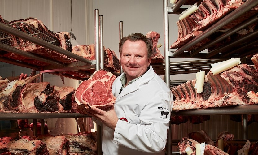 Nice to Meat butcher holding a cut of beef in the dry-age room